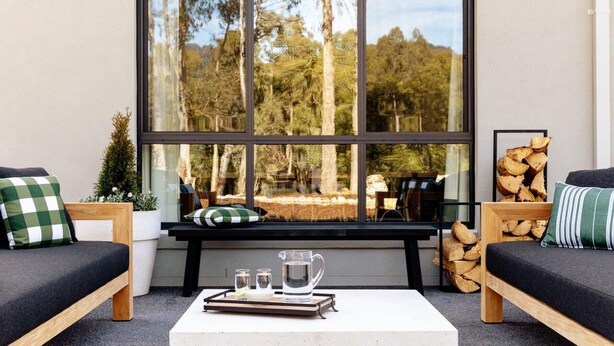 Un coin salon confortable avec une grande fenêtre, une petite table avec un plateau et une vue sur les arbres.