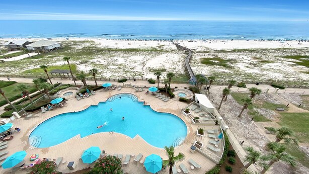 Een resort met een groot zwembad, toegang tot het strand en een boardwalk naar het strand.