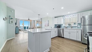 Een moderne keuken met witte kasten, een centraal eiland en een eethoek met uitzicht.