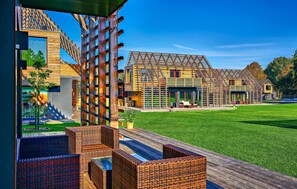 Een modern huis met een ruime buitenruimte, inclusief een houten terras en tuinmeubilair.