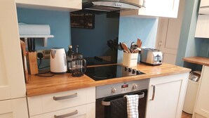 Eine kleine Küche mit weißen Schränken, einer Holz Arbeitsplatte, einem Herd und einem Toaster.