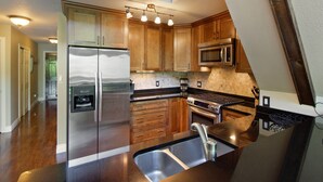 Une cuisine moderne avec des meubles en bois, des appareils en acier inoxydable et un plan de travail noir.