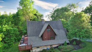 Une cabane en bois avec un toit en pente, une terrasse dotée de meubles d’extérieur et des fondations en pierre.
