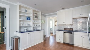 A kitchen with white cabinets, a stainless steel dishwasher, and a blue countertop.