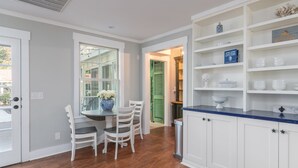 A kitchen with white cabinetry, a blue countertop, and a dining area with white chairs and a table.