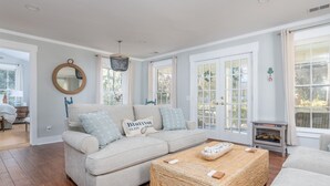 A living room with a sofa, a coffee table, a fireplace, and large windows.