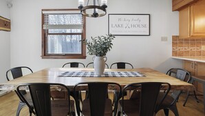 A dining area with a wooden table, black chairs, a chandelier, a potted plant, and a framed sign on the wall. - Lake front with Private Beach, Hot tub, Pool, Pickle Ball, March Dates available (Jim Thorpe)