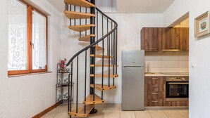 A kitchen with a spiral staircase, wooden cabinets, a refrigerator, and an oven. - Beautiful home in Karlobag with WiFi (Karlobag)