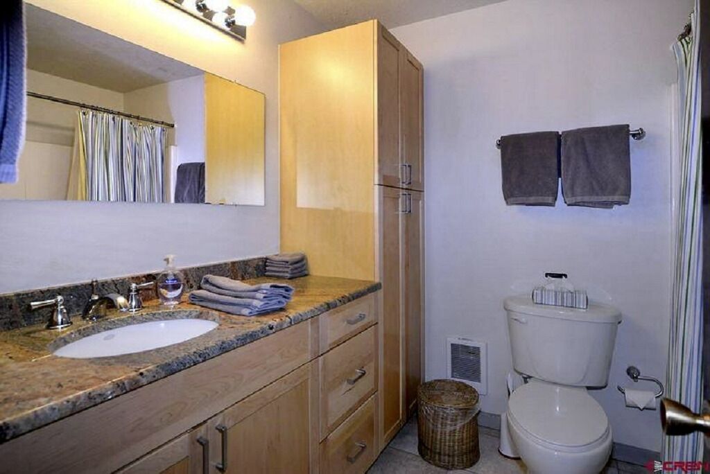 A bathroom with a sink, mirror, cabinet, toilet, and towels.