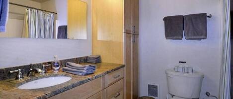 A bathroom with a sink, mirror, cabinet, toilet, and towels.