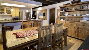 Een moderne keuken met houten kastjes, een roestvrijstalen koelkast, en een eethoek met een houten tafel en stoelen.