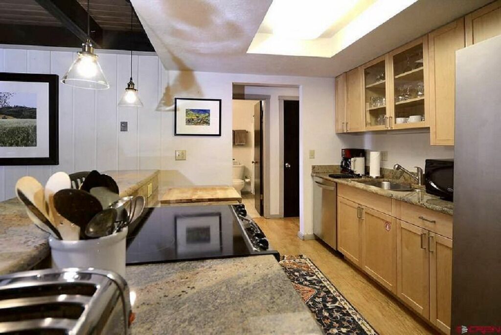 Une cuisine moderne dotée d’une cuisinière intégrée, de meubles en bois et d’un éclairage suspendu.