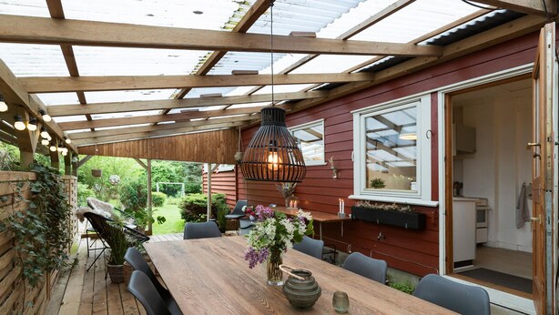 An outdoor dining area with a wooden table, chairs, and a hanging light fixture. - 3 bedroom pet friendly home in Hundested (Hundested)