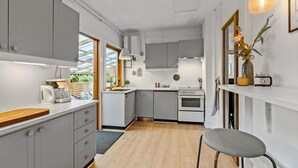 A modern kitchen with grey cabinets, a wooden countertop, a built-in oven, and a dining area with a chair. - 3 bedroom pet friendly home in Hundested (Hundested)