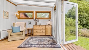 A cozy room with a wooden cabinet, a chair, a small table, and a large window. - 3 bedroom pet friendly home in Hundested (Hundested)