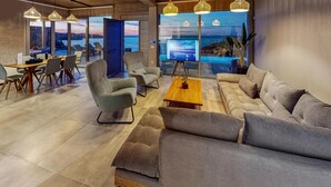 A modern lounge area with a large sofa, a coffee table, and a TV screen displaying a scenic view. - Awesome home in Gazi, Heraklio (Gazi, Heraklio)