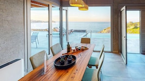 A dining area with a wooden table, chairs, and a view of the sea through large glass doors. - Awesome home in Gazi, Heraklio (Gazi, Heraklio)