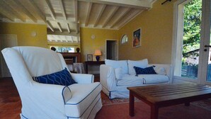 Un salon avec un fauteuil blanc, un canapé blanc et une table basse en bois.