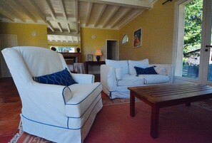 Un salon avec un fauteuil blanc, un canapé blanc et une table basse en bois.