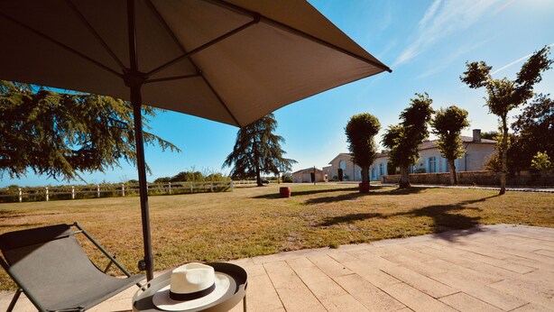Un espace patio comprenant une chaise pliante, une table avec un chapeau et un parasol.