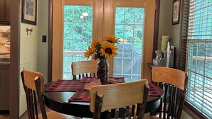 A dining area with a wooden table, four chairs, a chandelier, and a vase with sunflowers. - Cozy cabin, Babbling Brook & Mountain View w/fast Wi-Fi (Robbinsville)