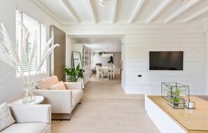 A spacious living area with a sofa, coffee table, and a TV mounted on the wall. - 3 bedroom cozy home in Lombardsijde (Lombardsijde)