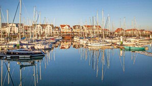 En småbåtshamn med många båtar förtöjda, omgiven av byggnader med röda tak.