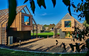 A modern wooden structure with a sloped roof, a small window, and a gravel pathway leading to it.