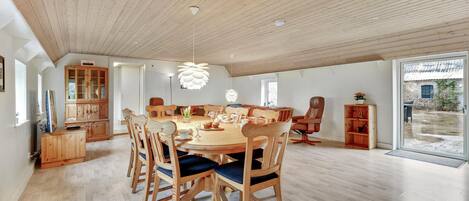 Een ruime eethoek met een houten tafel en stoelen, een grote kast en uitzicht op buiten.