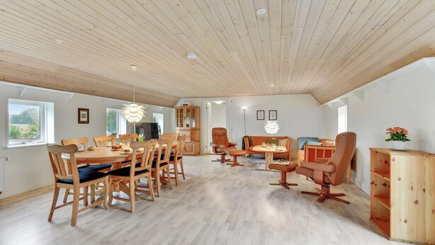 Un grand espace dédié à la salle à manger, avec une table et des chaises en bois, un téléviseur et un meuble.