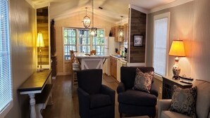 A cozy living room with a fireplace, a dining area with a large window, and a kitchen with wooden cabinets.