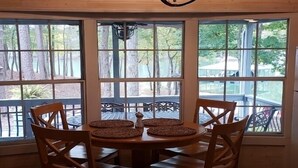 A dining area with a table and chairs, large windows, and a chandelier.
