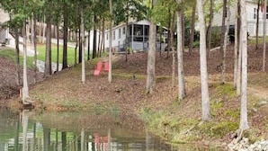 A cabin by a pond with a dock, surrounded by trees.