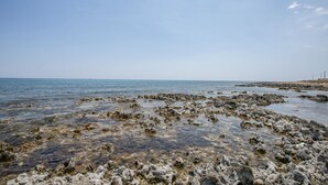 Una costa rocosa con agua cristalina y un barco a lo lejos.