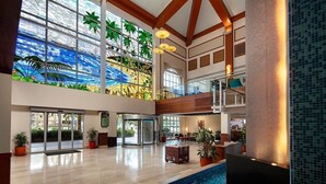 A spacious lobby with a large glass wall, a pool, and a high ceiling with wooden beams.