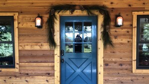 Una casetta di legno con una porta blu, due finestre e una ghirlanda sulla porta.
