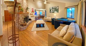 Cozy living room with a fireplace, sofa, and pool table, offering a comfortable seating area and dining space.