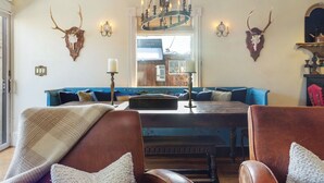A cozy living room with a blue sofa, leather armchairs, a wooden coffee table, and a chandelier.