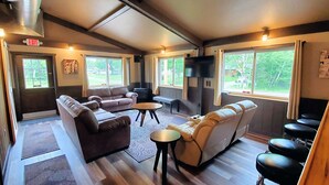Un intérieur chaleureux avec un canapé, des fauteuils, une petite table et un téléviseur.