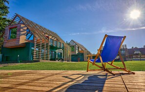 A modern building with a sloped roof, a wooden deck, and a blue beach chair. - 2 bedroom cozy home in Kuhlen-Wendorf (Kuhlen-Wendorf)