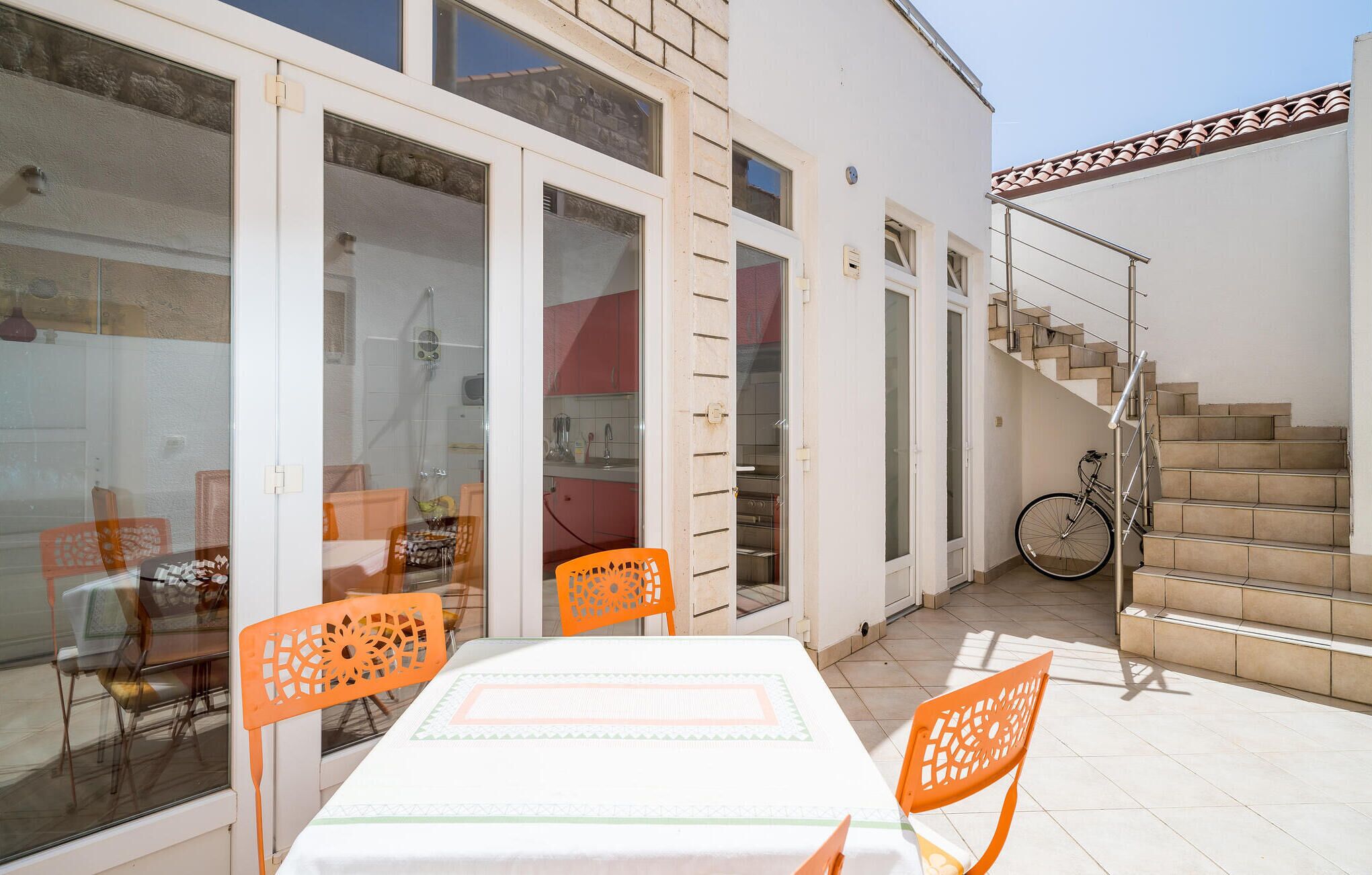 A patio area with a table and chairs, a bicycle, and a staircase leading to an upper level.