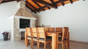 Ein Holzespeisesaal mit sechs Stühlen, einem Kamin aus Stein und einem Fliesenboden.