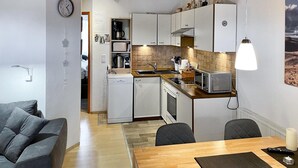 Eine kompakte Küche mit Geschirrspüler, Mikrowelle und Toaster. Es gibt einen Essbereich mit Tisch und Stühlen.