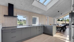 Eine moderne Küche mit einer großen Kochinsel, Holzschränken und Blick ins Freie.