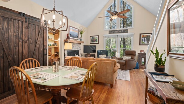 Un vaste espace de vie de style loft, doté d’un haut plafond, d’un plancher en bois, d’une table à manger avec des chaises, d’un canapé et d’un ventilateur de plafond.