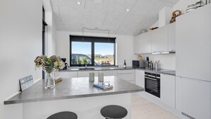 Une cuisine moderne dotée d’un îlot central, d’une grande fenêtre et offrant une vue sur la campagne.