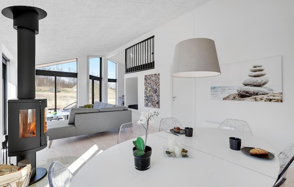 Cozy up by the round wood-burning stove in this stylish space, featuring a minimalist dining area and comfortable seating.