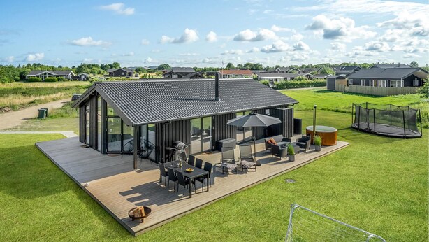 Une maison moderne dotée d’une grande terrasse, d’un espace salon extérieur et offrant une vue sur le quartier environnant.