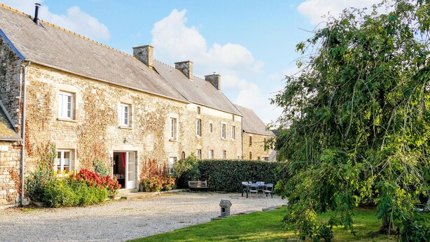 A stone building with a gravel driveway, a small garden with flowers, and a bench. - 4 bedroom pet friendly home in Portbail (Portbail)