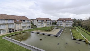 Een wooncomplex met meerdere twee verdiepingen tellende huizen, een centrale binnenplaats met een kleine vijver en verzorgde gazons.